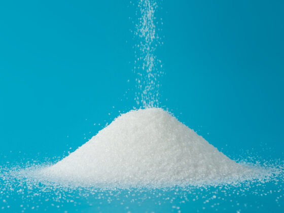 Heap Of Sugar With Pouring On Blue Background