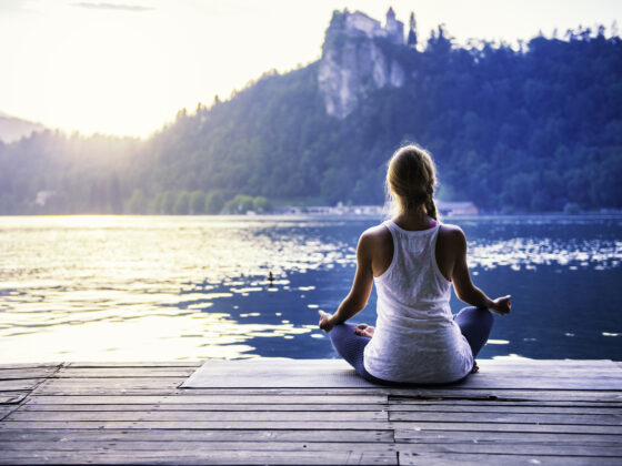 Young Woman Meditating By The Lake