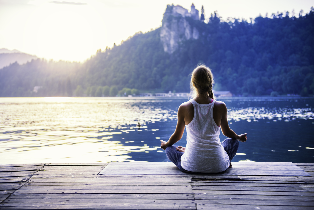 Young Woman Meditating By The Lake